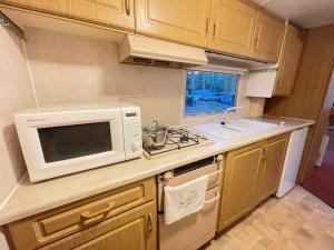 a small kitchen with a microwave and a stove at Your Caravan Hel in Hel