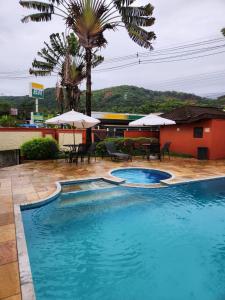 a swimming pool with tables and umbrellas next to a building at Apto Duplex com Mezanino in Juquei