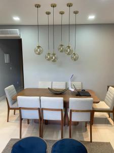 a dining room table with white chairs and lights at Cidade Nova, Gov. Valadares in Governador Valadares