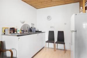 een keuken met witte kasten en twee zwarte stoelen bij Cosy private room in Slagelse