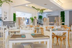 ein Esszimmer mit weißen Tischen und Stühlen in der Unterkunft Villaggio Poseidone Beach Resort - Hotel in Torre San Giovanni Ugento
