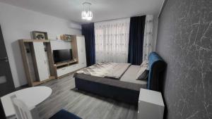 Schlafzimmer mit einem Bett, einem Tisch und einem TV in der Unterkunft Garsoniera NAVI in Onești