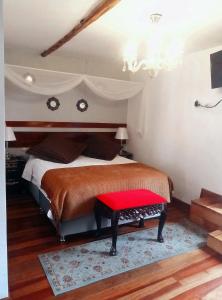um quarto com uma cama com um banco vermelho em Kori Gems Inn em Cusco