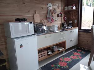 a kitchen with a refrigerator and a microwave at Tiny House Canjerana- Morro do Eurico - Praia Grande-SC in Praia Grande