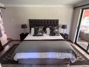 a bedroom with a large bed and two lamps at Hogsback Misty Oaks Cottage in Hogsback