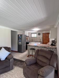 a living room with a couch and a kitchen at Hogsback Misty Oaks Cottage in Hogsback