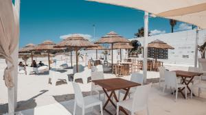 een strand met tafels, stoelen en parasols bij Villaggio Poseidone Beach Resort - Hotel in Torre San Giovanni Ugento