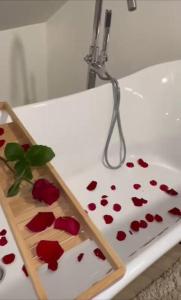Wellness Loft Huy في هوي: حوض استحمام أبيض مع بتلات ورد حمراء عليه