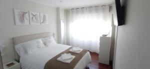 Un dormitorio con una cama blanca con dos pañuelos. en Val do Fragoso en Vigo