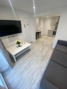 a living room with a tv and a white table at Erin Guest House in Bristol