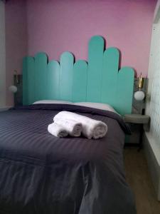 a bed with a blue headboard and two towels at Unique City Centre Apartments in Nicosia