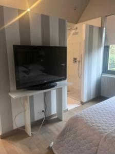 1 dormitorio con TV de pantalla plana en la pared en La Demeure de l'Ile, en Craon