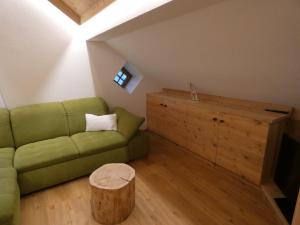 a living room with a green couch and a wooden cabinet at Casa Gogn in San Vigilio Di Marebbe