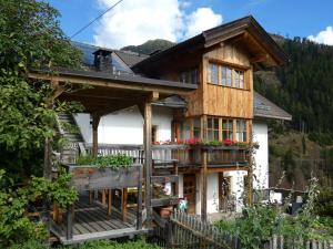 a wooden house with a balcony in the mountains at Casa Gogn in San Vigilio Di Marebbe