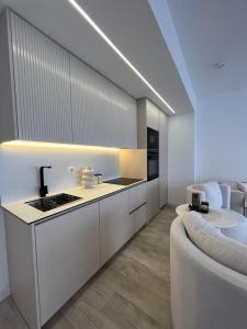 a kitchen with white cabinets and a sink and a couch at Chameleon Studio in Ferizaj
