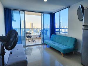 a living room with a blue couch and a large window at Apartamento Con Vista al Mar - Central in Cartagena de Indias