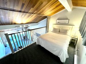 a bedroom with a white bed and a balcony at Oceanfront Loft - amazing views! in Qualicum Beach