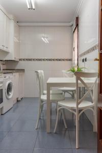 cocina con mesa, sillas y lavadora en AH Delux3Rooms Campus Milán VUT6519AS, en Oviedo