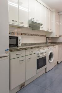 una cocina con gabinetes blancos y una lavadora y secadora en AH Delux3Rooms Campus Milán VUT6519AS, en Oviedo