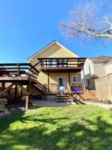 a yellow house with a porch and a deck at Cozy Suite-Walk to the Falls! in Niagara Falls