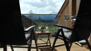 een balkon met 2 stoelen en een tafel met wijnglazen bij Leben!Pur - Alpenlofts in Bad Mitterndorf