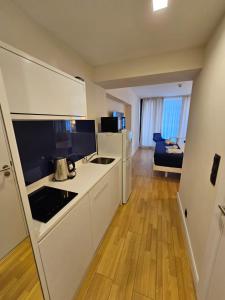 een keuken met witte apparatuur en een kamer met een bank bij Sea View Lux Aparthotel in ORBi City Batumi in Batoemi