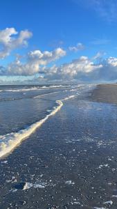 a beach with water and foam on the sand at Bij Risje dorp in Ballum