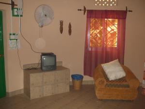 ein Wohnzimmer mit einem TV, einem Stuhl und einem Ventilator in der Unterkunft Camping-Sukuta & Lodge in Sukuta
