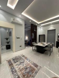 een woonkamer met een tafel en stoelen en een tapijt bij شقه مودرن أنيقة in Riyad