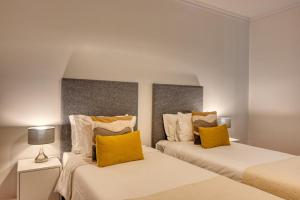 two beds with yellow pillows in a bedroom at Encarnacao Apartment, a Home in Madeira in Funchal