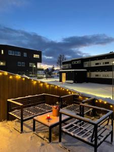 a patio with two benches and a table with lights at Cosy and centrally located apartment in Tromsø