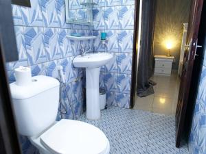 a blue and white bathroom with a toilet and sink at Apparts meublés Tigson in Yaoundé