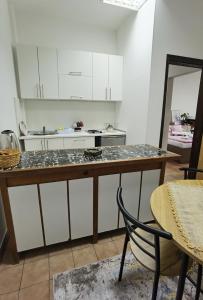 a kitchen with white cabinets and a table and a chair at Apartman Pearl in Sarajevo +7 photos
