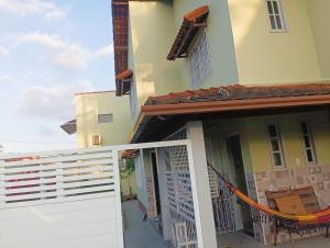 a house with a white fence and a porch at Jardim das orquideas 2 in Rio das Ostras