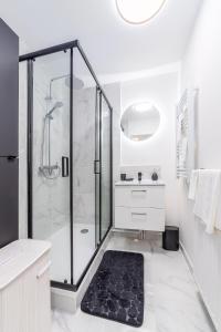 een witte badkamer met een douche en een zwart tapijt bij Appartement en face gare d'Evry - Proche Paris & Disney - Easy check in - Arrivée autonome -Place de parking privative - Wifi in Évry-les-Châteaux