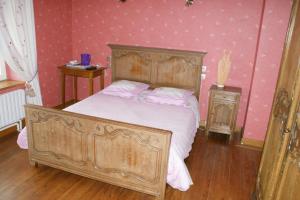 a bedroom with a wooden bed with white sheets and pink walls at Le Relais Postal in Courson