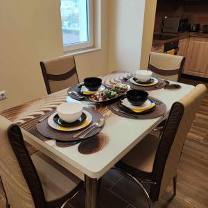 einen Esstisch mit Tellern und Schüsseln. in der Unterkunft DB Luxury Apartment in Weliko Tarnowo