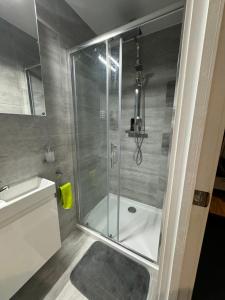 a shower with a glass door next to a sink at Mathews Den in Thamesmead