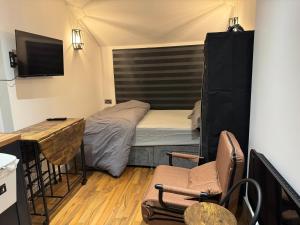 a small room with a bed and a desk and chairs at Mathews Den in Thamesmead