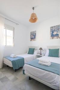 2 camas en una habitación con paredes blancas en Adosado Cigüeñas IV-Islantilla Golf, en Huelva