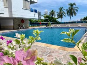una piscina con flores púrpuras frente a un edificio en Aparta Estudio Vista Piso 20 en Cartagena de Indias