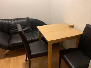 un canapé en cuir et une table avec deux chaises dans l'établissement Appartement Römerstr 3 Zimer, à Essen