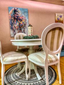 ein Esszimmer mit 2 Stühlen, einem Tisch und einem Gemälde in der Unterkunft Apartman Diana in Sremska Mitrovica