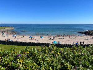 a group of people on a beach near the ocean at Cosy Seaside Home in Groomsport