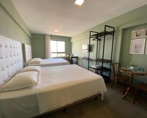 ein Schlafzimmer mit einem großen weißen Bett und einem Tisch in der Unterkunft ILUSION FLAT-Ponta Negra in Natal