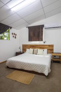 Schlafzimmer mit einem großen weißen Bett mit einem Kopfteil aus Holz in der Unterkunft Hotel Michanti in El Zonte