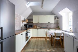 a kitchen with white cabinets and a table with chairs at River View City Centre- Free Parking in Inverness