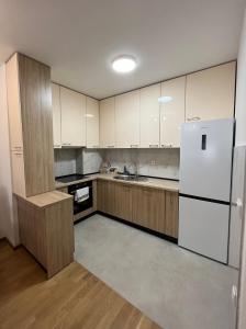 a kitchen with a white refrigerator and wooden cabinets at Apartman Vista Banja Luka in Banja Luka