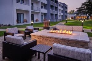 Courtyard Chicago Highland Park/Northbrook في هايلاند بارك: حفرة نار مع كراسي وطاولات أمام مبنى