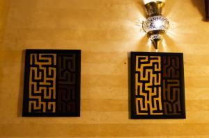 two black and gold frames on a wall with a light at Riad Dar Alhambra in Marrakech